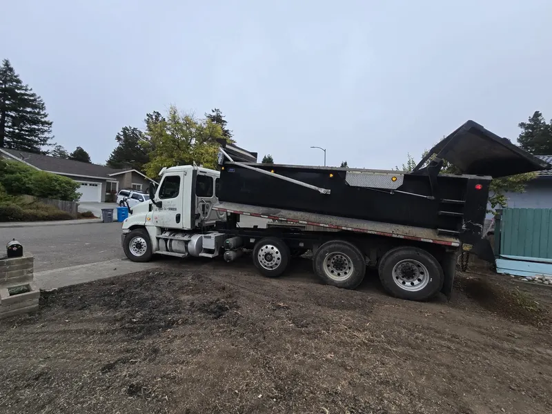 Dump truck positioned at a residential property for a fill dirt delivery