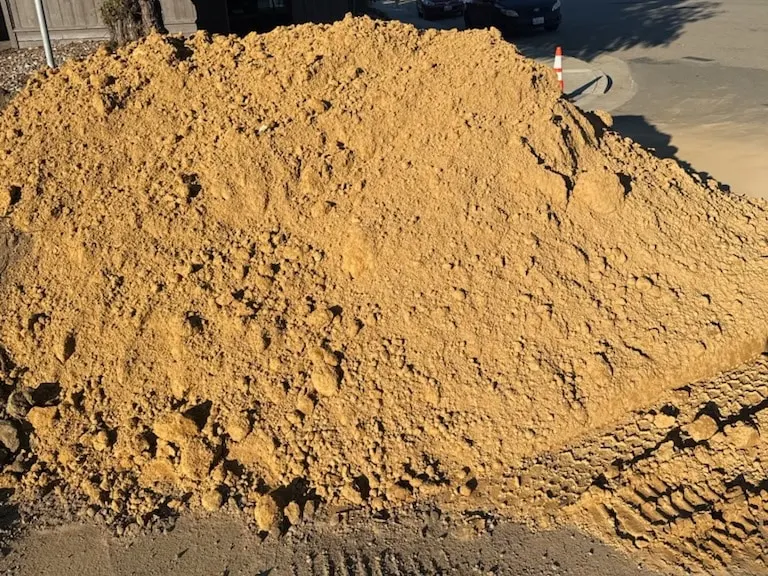 Large pile of tan fill dirt beside a residential street
